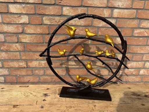 Vogelskulptur auf einem bronzenen Zweig