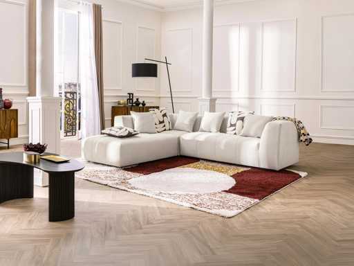 Grote beige fijn geribbelde ribfluweel bank in de linkerhoek van Maison Céphy