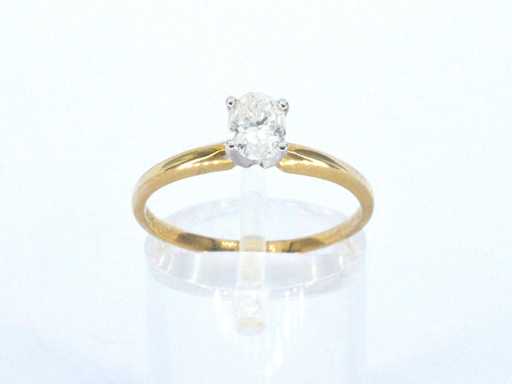 Gold solitaire ring with an oval cut diamond in white gold setting